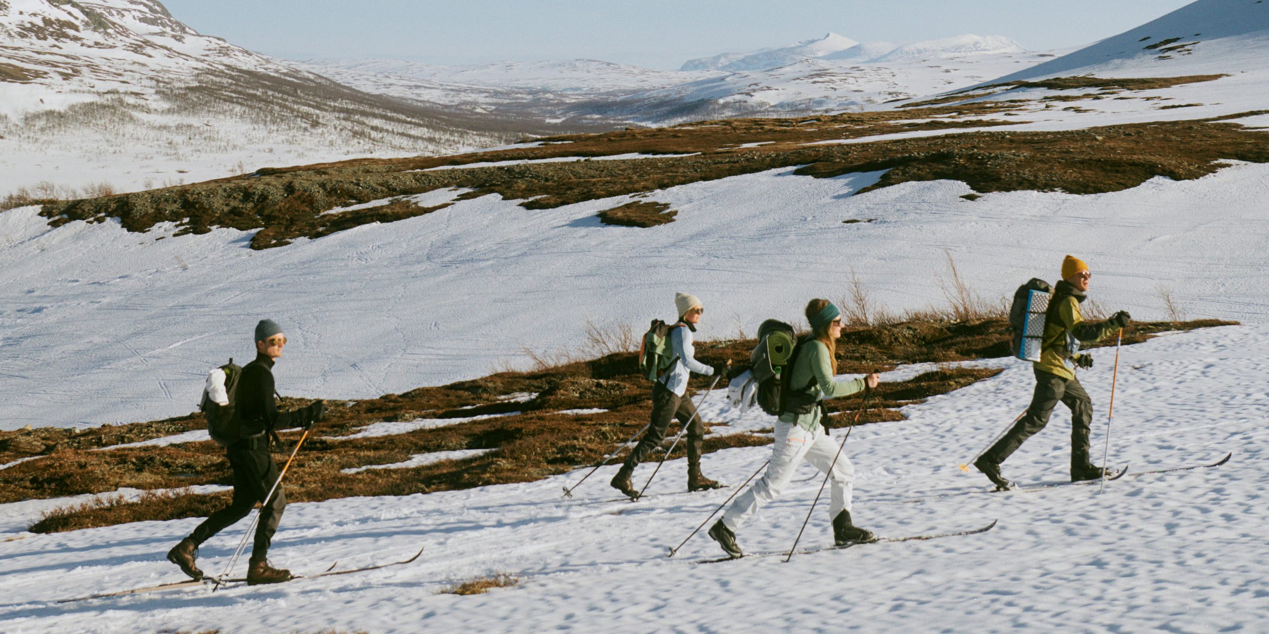 Fyra personer åker längdskidor på ett fjäll.