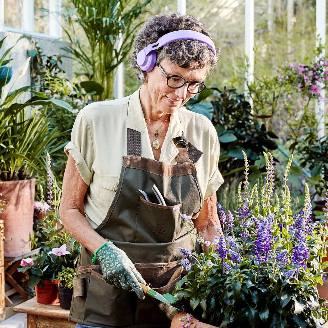 En äldre kvinna planterar i ett växthus.