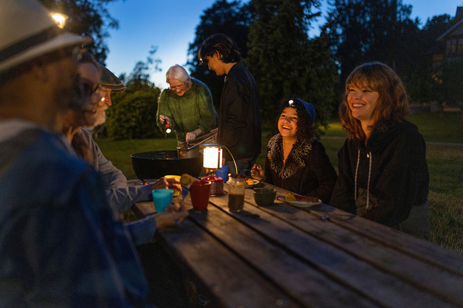 Flera personer sitter runt en bord utomhus på kvällen. MSB